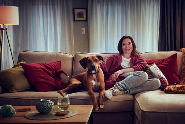 A happy person on the couch watching TV with a dog