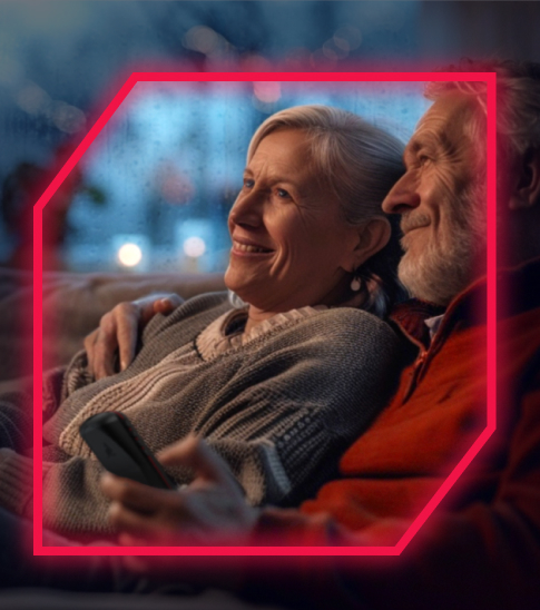 A man and woman sit on a couch smiling