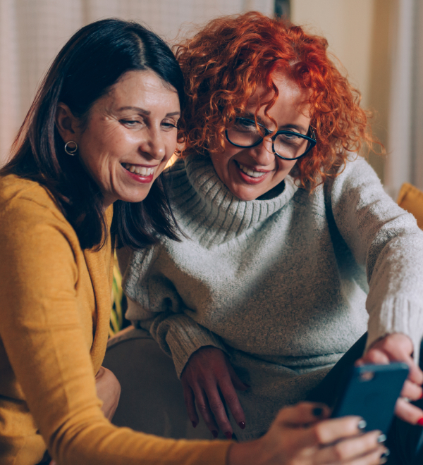 Two women look at their phone using Boost Mobile
