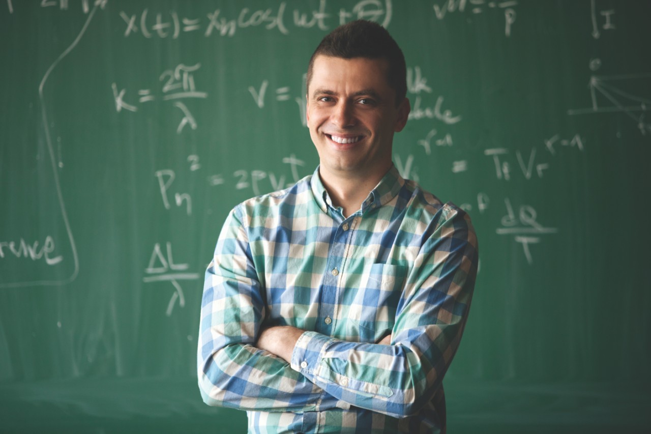 young cheerful professor in front of blackboard