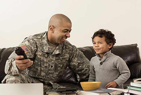 Military man enjoying TV with a child